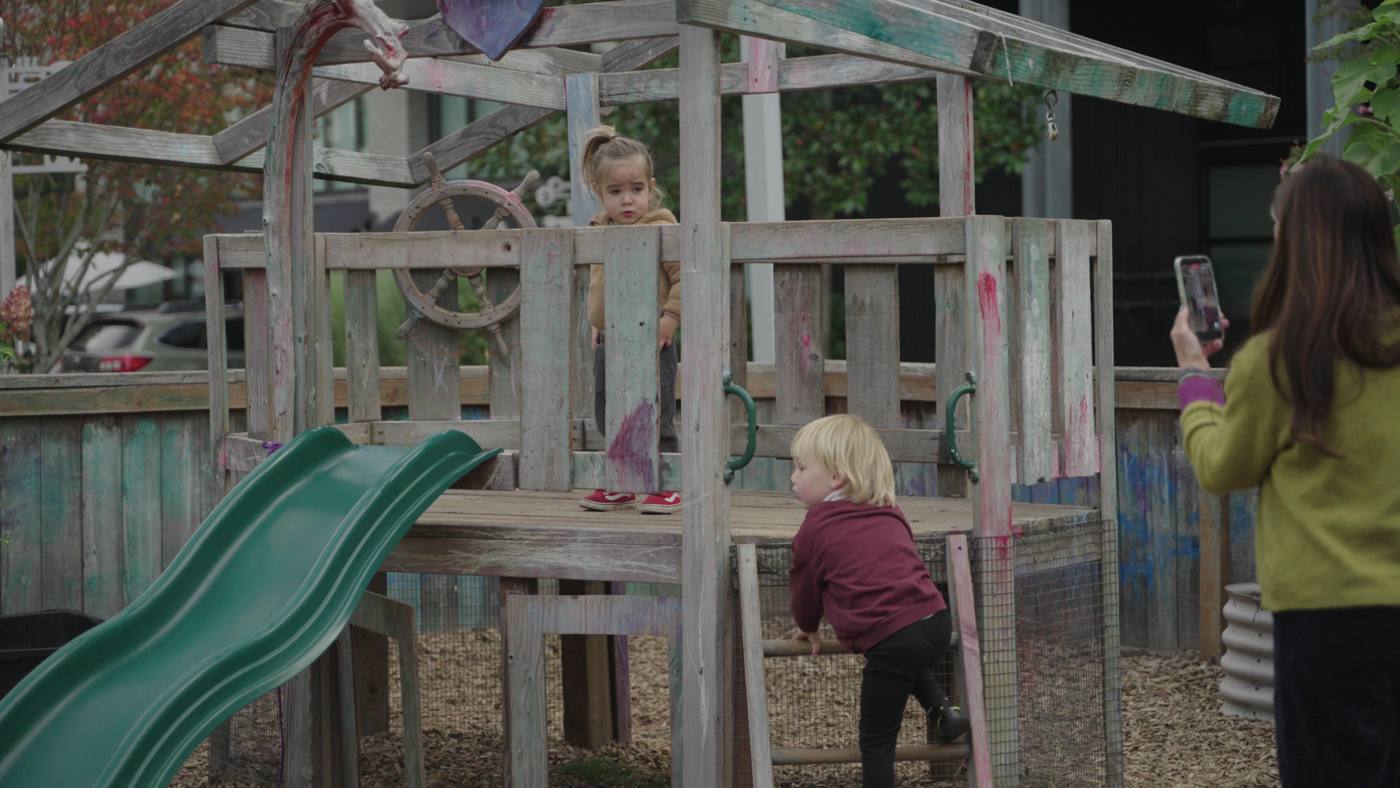 The yard at one of the schools, children on the play structure from behind